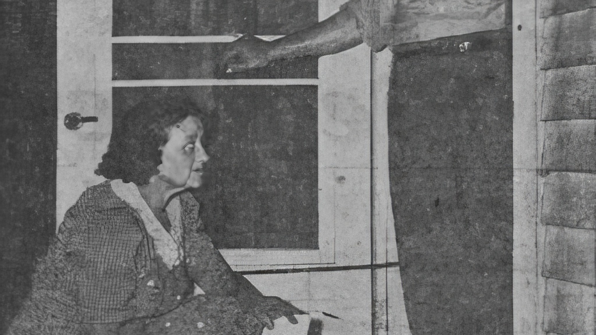 Archival photograph: a woman crouching beside a screen door, looking at a man’s arm reaching toward the latch, from the Mattoon gas scare